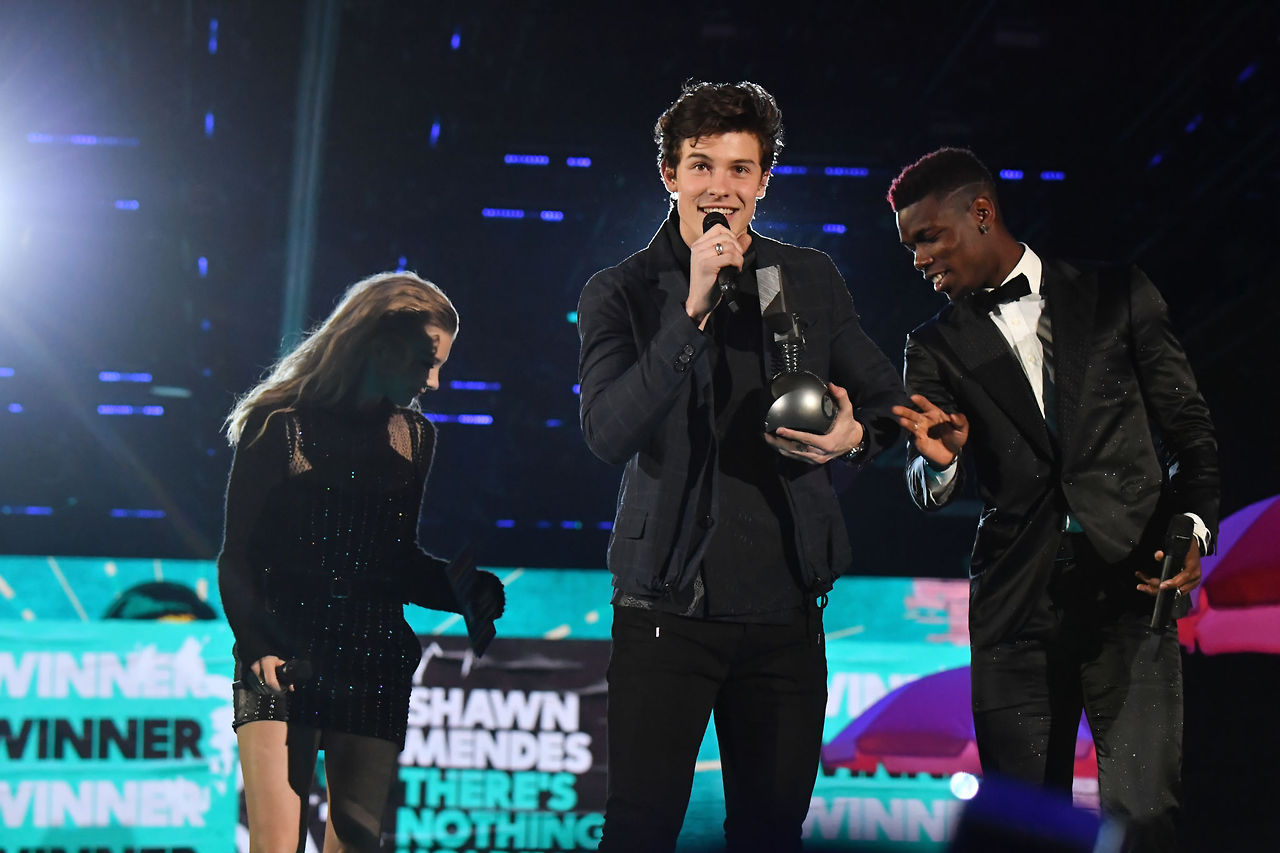 Actress Natalie Dormer and Manchester United French professional footballer Paul Pogba (R) present the award for Best Song to Shawn Mendes (C) on stage during the 2017 MTV EMAs held at the SSE Arena on November 12, 2017 in London, England